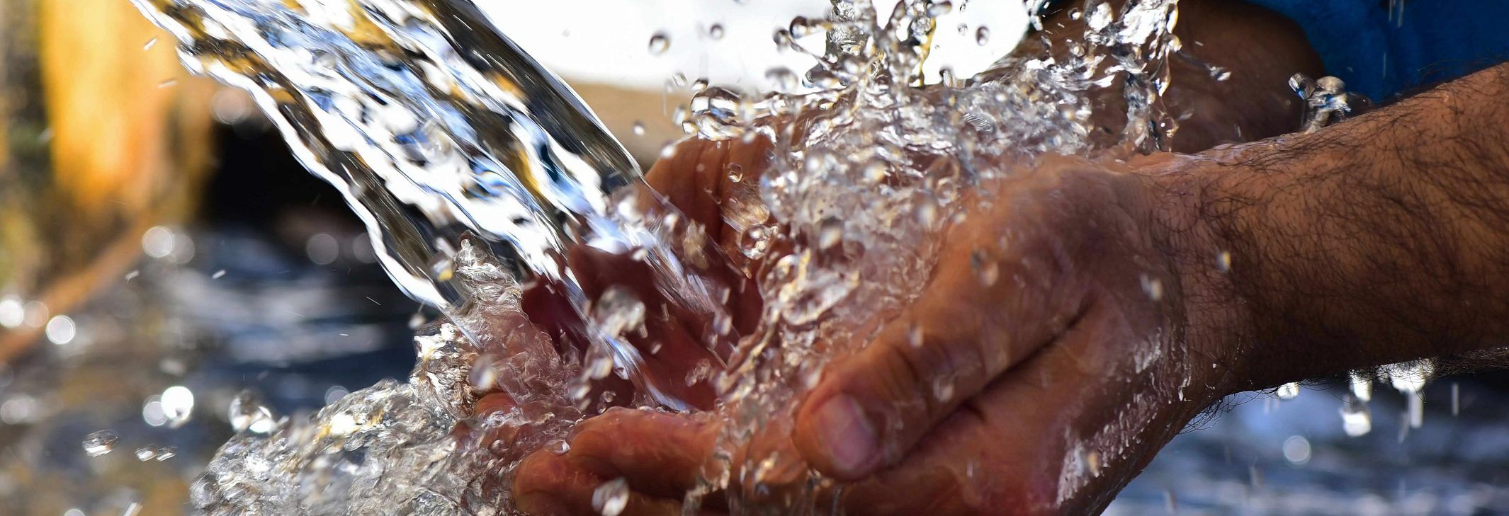 Manos recibiendo un chorro de agua limpia.