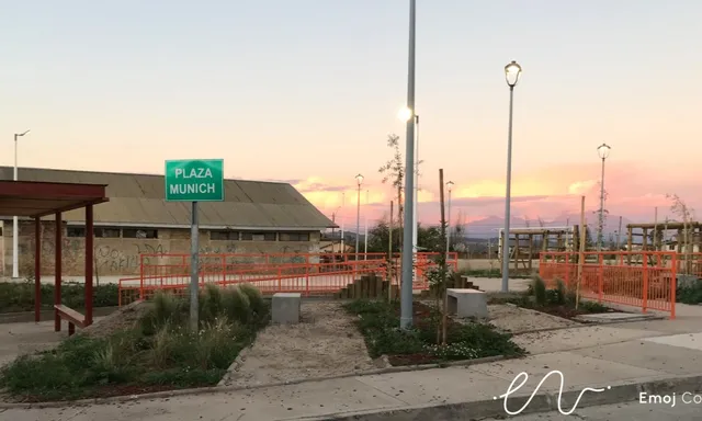 Plaza Munich en Quilpué al atardecer, con senderos, jardineras, luminarias y barandas naranjas.