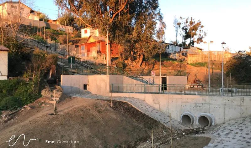 Plaza en una ladera de Quilpué con escaleras, muros de contención y barandas, al atardecer.