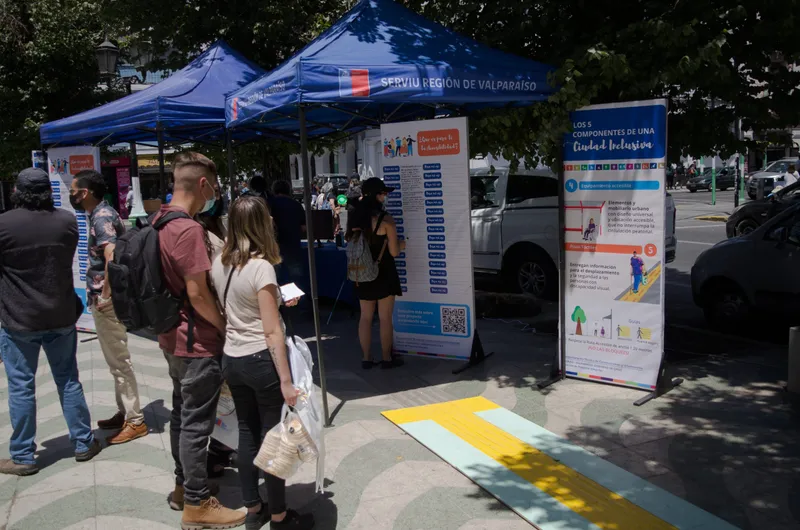 Vecinos recorren paneles informativos bajo toldos del Serviu Región de Valparaíso en una actividad en la calle.